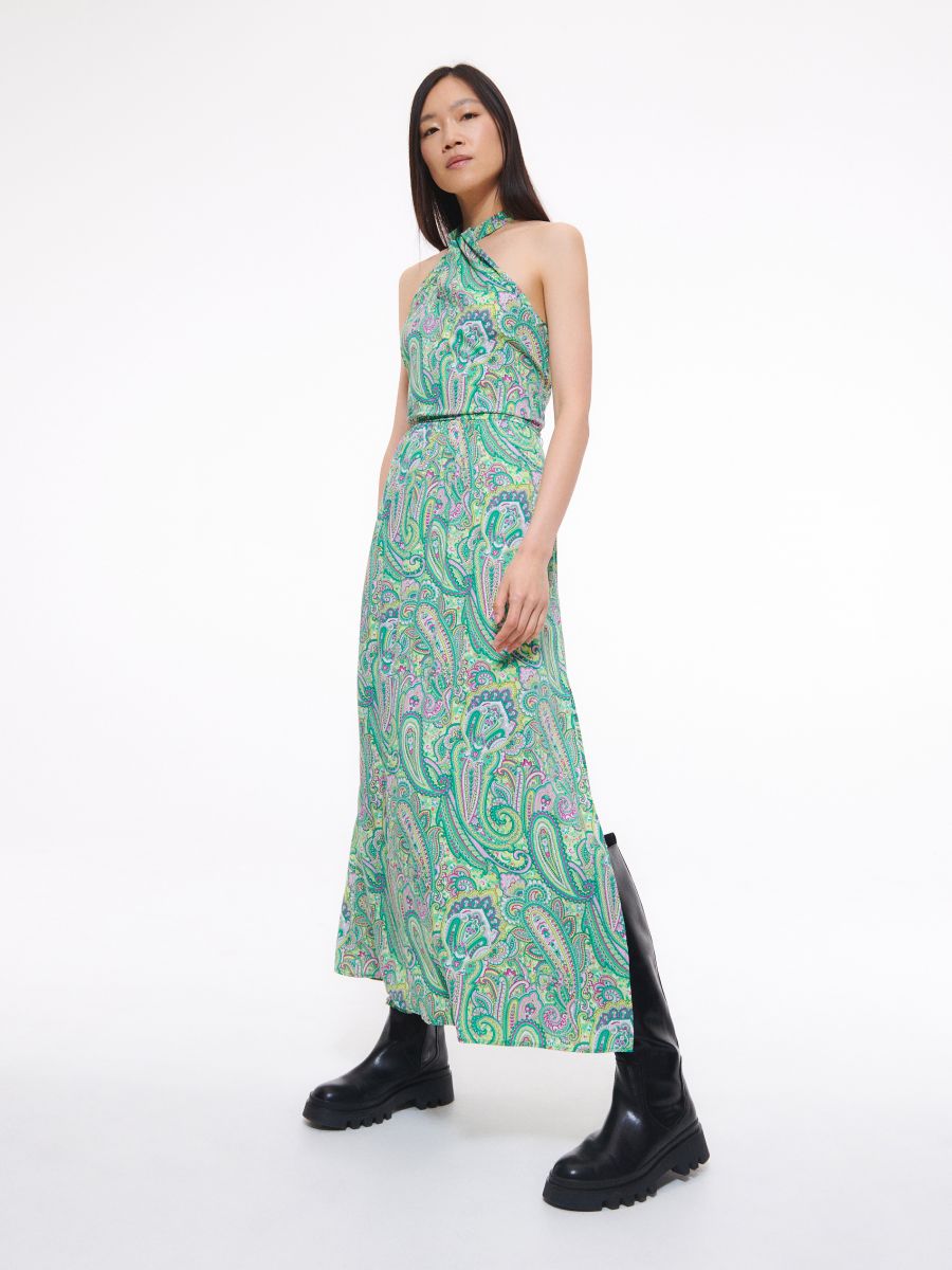 Reserved maxi dress in green paisley print. This dress has a relaxed design with a 70s style paisley print and halter neck. It is nipped at the waist with an elasticated waistband and has 
side splits for movement. On trend maxi length. 