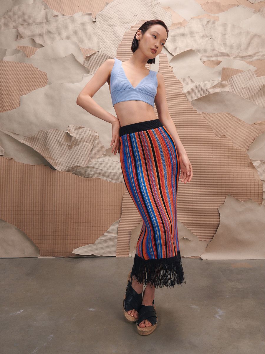 Multi-coloured vertically striped knitted midi skirt with elasticated waist and fringing detail at the hem. 